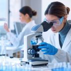 Young scientists conducting research investigations in a medical laboratory, a researcher in the foreground is using a microscope